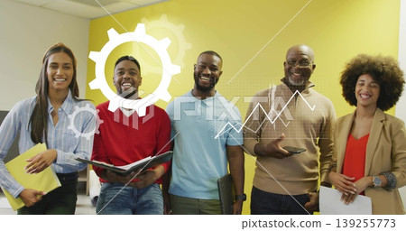 Collaborating team of five showing data graphic by yellow wall in office holding papers and devices Collaborating team of five showing data graphic by yellow wall in office holding papers and devices 139255773
