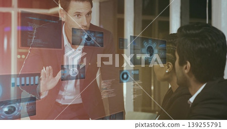 Presenting burgundy-suited male gesturing toward holographic data display in office conference room Presenting burgundy-suited male gesturing toward holographic data display in office conference room 139255791