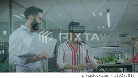 Interacting Hispanic woman wearing VR headset in open-plan office, with coworker using laptop Interacting Hispanic woman wearing VR headset in open-plan office, with coworker using laptop 139255812