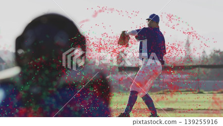 Winding right-handed pitcher releasing baseball on mound at baseball stadium, with catcher's helmet Winding right-handed pitcher releasing baseball on mound at baseball stadium, with catcher's helmet 139255916