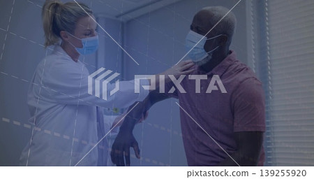 Female doctor assessing male patient shoulder range in exam chair, with lab coat and surgical masks Female doctor assessing male patient shoulder range in exam chair, with lab coat and surgical masks 139255920