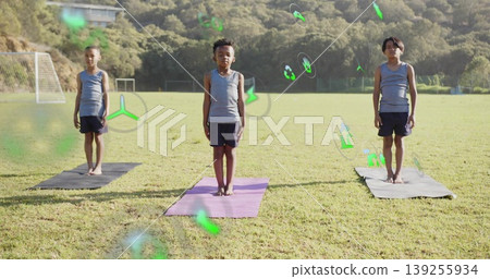 Standing three boys in sportswear on yoga mats in grassy field, with soccer goal, floating icons Standing three boys in sportswear on yoga mats in grassy field, with soccer goal, floating icons 139255934