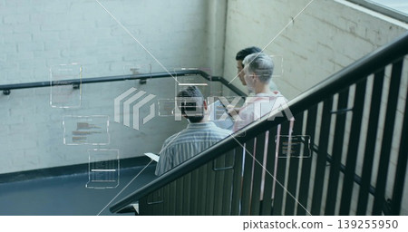 Collaborating developers viewing digital code overlays in office stairwell with tablet and railing Collaborating developers viewing digital code overlays in office stairwell with tablet and railing 139255950
