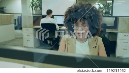 Working woman wearing blazer and glasses typing at office cubicle, with computer monitor keyboard Working woman wearing blazer and glasses typing at office cubicle, with computer monitor keyboard 139255962