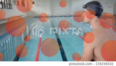 Sitting male swimmer at lap pool, with swim cap, goggles, briefs and lane ropes, copy space Sitting male swimmer at lap pool, with swim cap, goggles, briefs and lane ropes, copy space 139256010
