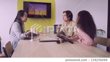 Collaborating team in boardroom wearing formal wear discussing renewable energy with scale models Collaborating team in boardroom wearing formal wear discussing renewable energy with scale models 139256089