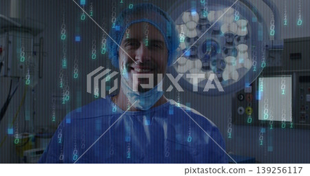 Standing surgeon pulling mask down in blue scrubs under surgical lamp in OR, with binary overlay Standing surgeon pulling mask down in blue scrubs under surgical lamp in OR, with binary overlay 139256117