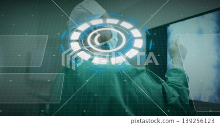 Examining Indian surgeon in surgical gown reviewing scan display in clinical bay with HUD overlay 139256123