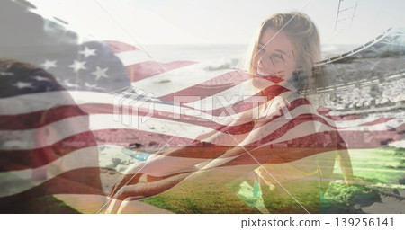 Smiling woman in yellow top sitting on grass facing man, with American flag overlay and bleachers Smiling woman in yellow top sitting on grass facing man, with American flag overlay and bleachers 139256141