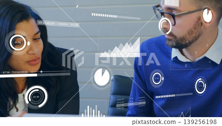Two business professionals reviewing analytics in conference room at table, with digital overlay 139256198