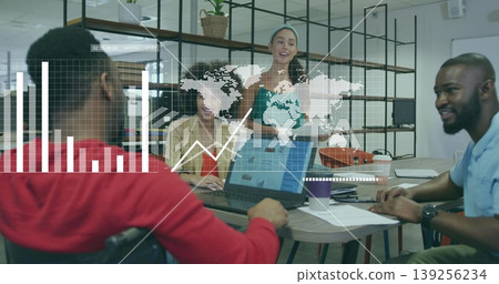 Presenting charts and world map overlay in green jumpsuit at meeting table, with laptop coffee cup 139256234