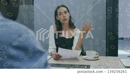 Candidate in business attire holding documents and gesturing in meeting room with coffee and cookie Candidate in business attire holding documents and gesturing in meeting room with coffee and cookie 139256261