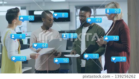 Four professionals in business attire reviewing social media metrics in office, with laptops docs Four professionals in business attire reviewing social media metrics in office, with laptops docs 139256262