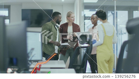 Holding laptop on adjustable stand, man in green shirt leading discussion in office, with tablet Holding laptop on adjustable stand, man in green shirt leading discussion in office, with tablet 139256276