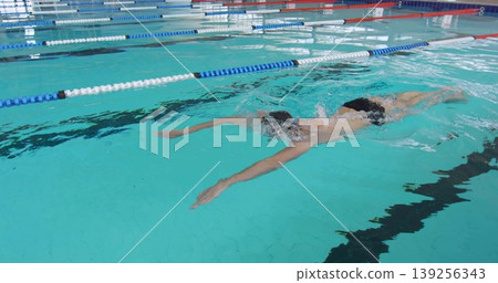 Cutting swimmer front crawling with swim cap goggles in turquoise water pool lane, with dividers Cutting swimmer front crawling with swim cap goggles in turquoise water pool lane, with dividers 139256343