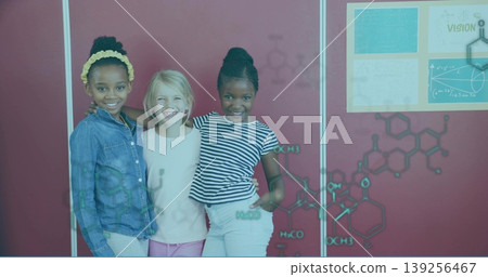 Standing three student girls smiling in science classroom, with Vision poster and chemical diagrams Standing three student girls smiling in science classroom, with Vision poster and chemical diagrams 139256467