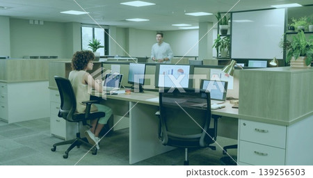 Working woman focusing on laptop and monitor charts at open office desk, colleague pointing Working woman focusing on laptop and monitor charts at open office desk, colleague pointing 139256503