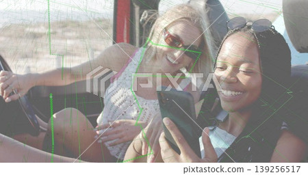 Smiling friends wearing crocheted tank top taking selfie in convertible in desert, with smartphone Smiling friends wearing crocheted tank top taking selfie in convertible in desert, with smartphone 139256517