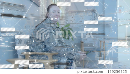 Holding tablet, soldier in uniform sitting on armchair in lounge showing data overlay with plant Holding tablet, soldier in uniform sitting on armchair in lounge showing data overlay with plant 139256525