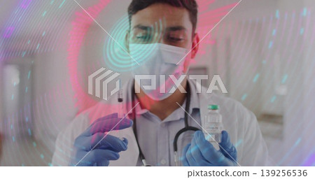Medical doctor wearing lab coat preparing vaccine in treatment room, with COVID-19 vial and syringe Medical doctor wearing lab coat preparing vaccine in treatment room, with COVID-19 vial and syringe 139256536