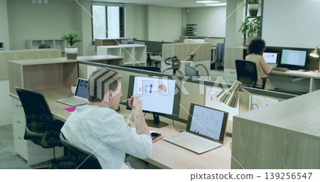 Office worker eating snack bowl in open-plan office, reviewing charts on dual monitors, copy space Office worker eating snack bowl in open-plan office, reviewing charts on dual monitors, copy space 139256547