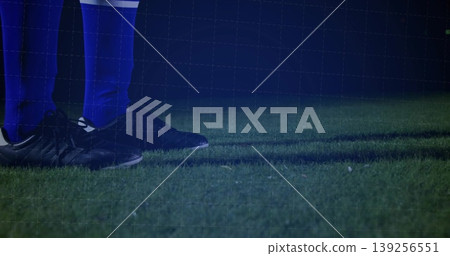 Displaying feet of soccer player standing on night turf, with blue socks, black cleats, copy space Displaying feet of soccer player standing on night turf, with blue socks, black cleats, copy space 139256551