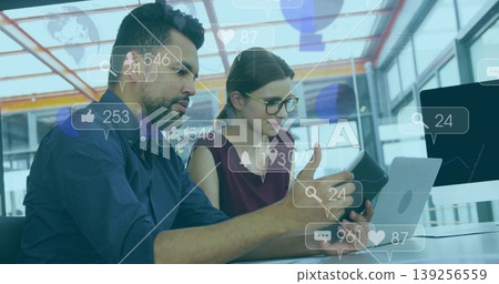 Collaborating coworkers analyzing social media engagement at modern office desk, with tablet laptop 139256559