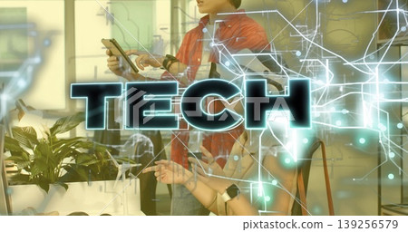 Standing tech pro in red shirt tapping tablet using TECH overlay at office desk, with smartwatches 139256579