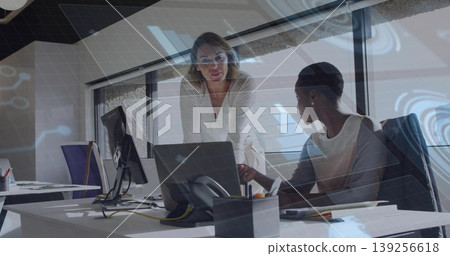 Collaborating two businesswomen reviewing laptop screen in modern office, with notebooks, telephone Collaborating two businesswomen reviewing laptop screen in modern office, with notebooks, telephone 139256618