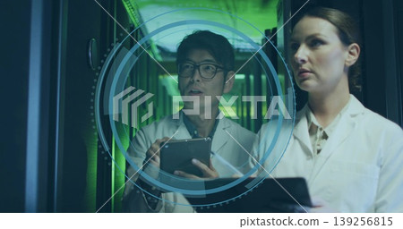 Two IT technicians projecting and analyzing 3D interface in hall, with server racks and tablets Two IT technicians projecting and analyzing 3D interface in hall, with server racks and tablets 139256815