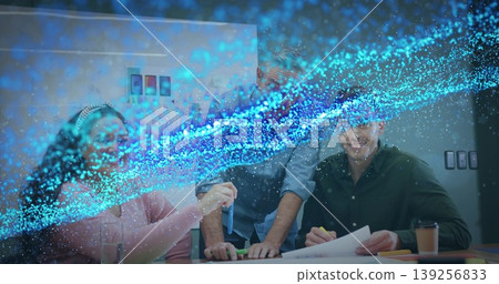 Overlaying digital effects, woman in pink sweater and colleagues examining blue test tube in office Overlaying digital effects, woman in pink sweater and colleagues examining blue test tube in office 139256833