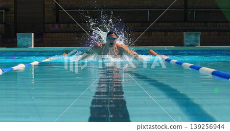 Doing breaststroke male swimmer wearing swim cap, goggles gliding in outdoor pool with lane ropes Doing breaststroke male swimmer wearing swim cap, goggles gliding in outdoor pool with lane ropes 139256944