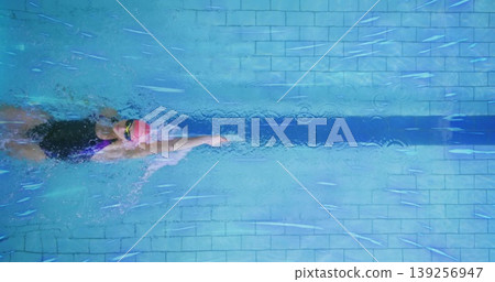 Gliding swimmer slicing through water at lap pool, with pink cap and tinted goggles, copy space Gliding swimmer slicing through water at lap pool, with pink cap and tinted goggles, copy space 139256947