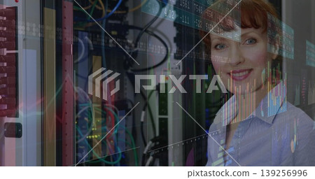 Smiling female IT expert monitoring network hardware in data center, chart overlays, copy space 139256996