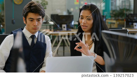 Gesturing colleagues in business attire reviewing laptop in open office, with whiteboard notes Gesturing colleagues in business attire reviewing laptop in open office, with whiteboard notes 139257023