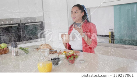 Woman in red blazer checking smartphone and holding mug at kitchen, with juice carafe and berries Woman in red blazer checking smartphone and holding mug at kitchen, with juice carafe and berries 139257061