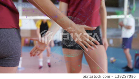 High-fiving volleyball players wearing red jerseys on gymnasium court, with net and sports bag High-fiving volleyball players wearing red jerseys on gymnasium court, with net and sports bag 139257086