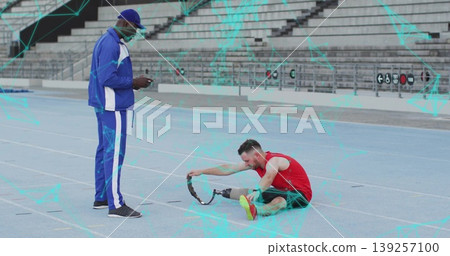 Seeing coach in tracksuit checking phone as athlete adjusting prosthetic blade on track, copy space Seeing coach in tracksuit checking phone as athlete adjusting prosthetic blade on track, copy space 139257100