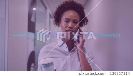 Talking woman in shirt juggling smartphone and lidded cup in office corridor, waveform overlay Talking woman in shirt juggling smartphone and lidded cup in office corridor, waveform overlay 139257114