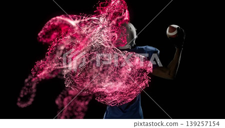 Cocking arm holding football, African American player on set with white helmet, pads, red particles 139257154