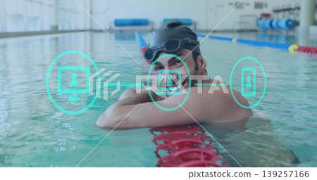 Resting swimmer wearing black cap, goggles on red lane divider at lap pool, with blue mats Resting swimmer wearing black cap, goggles on red lane divider at lap pool, with blue mats 139257166