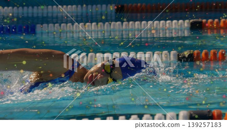 Swimming female wearing one-piece swimsuit and swim cap navigating pool lane with floating dividers Swimming female wearing one-piece swimsuit and swim cap navigating pool lane with floating dividers 139257183