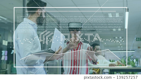 Gesturing man wearing AR headset using virtual interface in tech office, with laptop and monitors Gesturing man wearing AR headset using virtual interface in tech office, with laptop and monitors 139257257