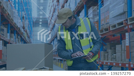 Leaning warehouse worker inspecting inventory using tablet in long aisle, with boxes and racks Leaning warehouse worker inspecting inventory using tablet in long aisle, with boxes and racks 139257270