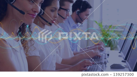 Typing call center agents wearing headsets at office desk, with keyboards, wave graphic overlay Typing call center agents wearing headsets at office desk, with keyboards, wave graphic overlay 139257300