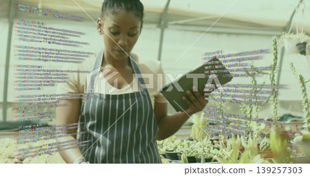 Inspecting plants woman wearing striped apron and holding tablet in greenhouse with succulents Inspecting plants woman wearing striped apron and holding tablet in greenhouse with succulents 139257303