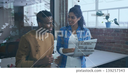 Discussing code snippets while software developers viewing laptop at brick office, with coffee mug Discussing code snippets while software developers viewing laptop at brick office, with coffee mug 139257343