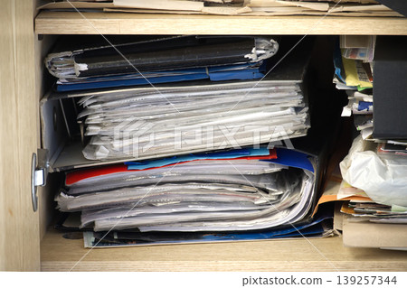 A packed cabinet shows an overwhelming amount of files and documents. 139257344