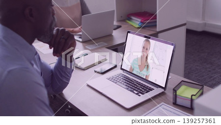 Leaning mature man focusing on online call on laptop in office cubicle, with notebook, copy space 139257361