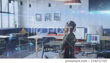 Analyzing woman holding smartphone viewing chart on monitor at open-plan office, copy space 139257397